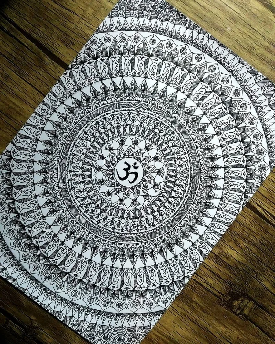 ماندالای دایره‌ای مدادی با نماد اُم در مرکز روی میز چوبی